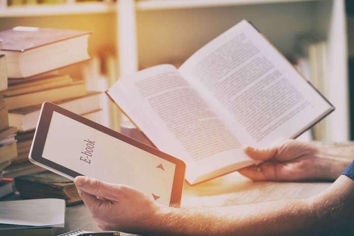 Das Foto zeigt die Hände eines Mannes, der in der einen hand ein E-Book_Reader und in der anderen Hand ein gedrucktes Buch hält.