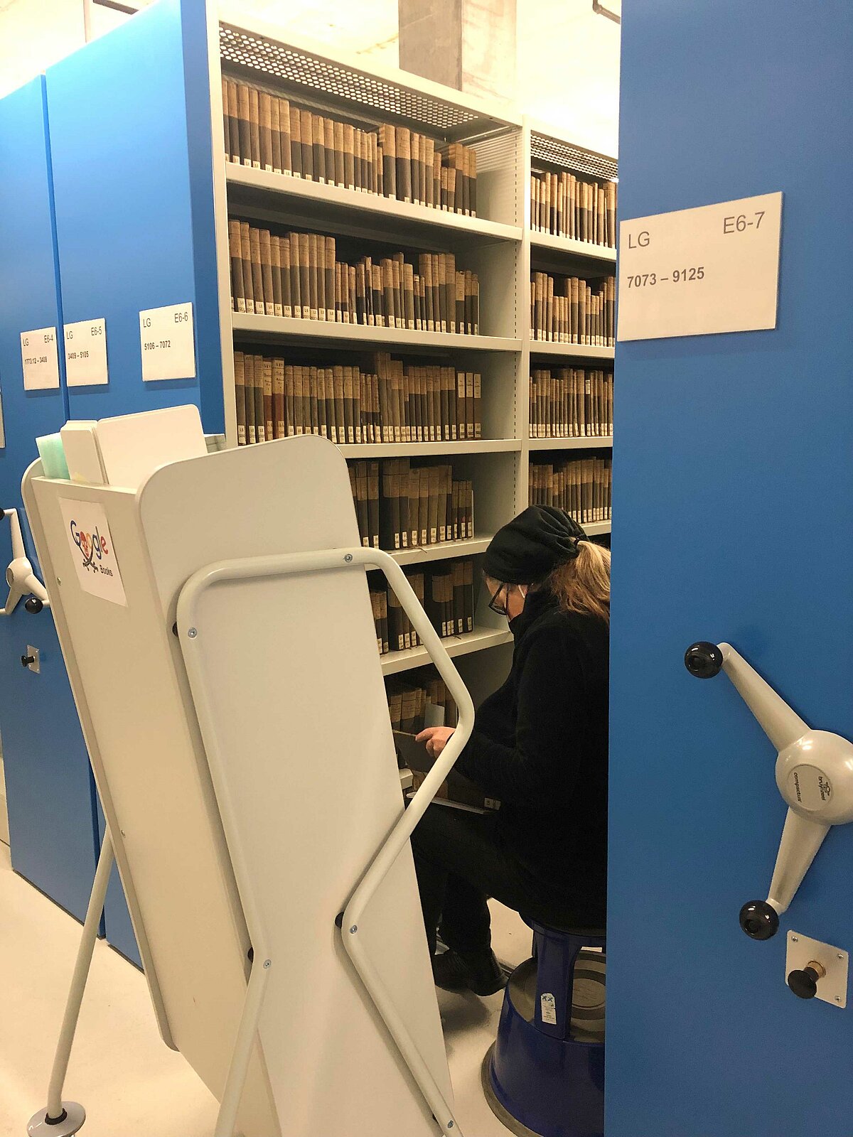 Eine Mitarbeiterin der Universitätsbibliothek Bern holt Bücher aus dem magazin und stellt sie in einen Bücherwagen. Später werden die Bücher für das Google-Books-Programm digitalisiertl. 